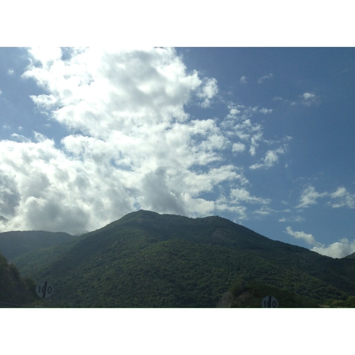 A mountain with a speed limit sign of 100 km/h.