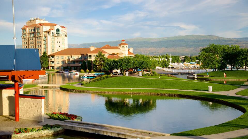 A park with a pond, boats, and buildings in the background.