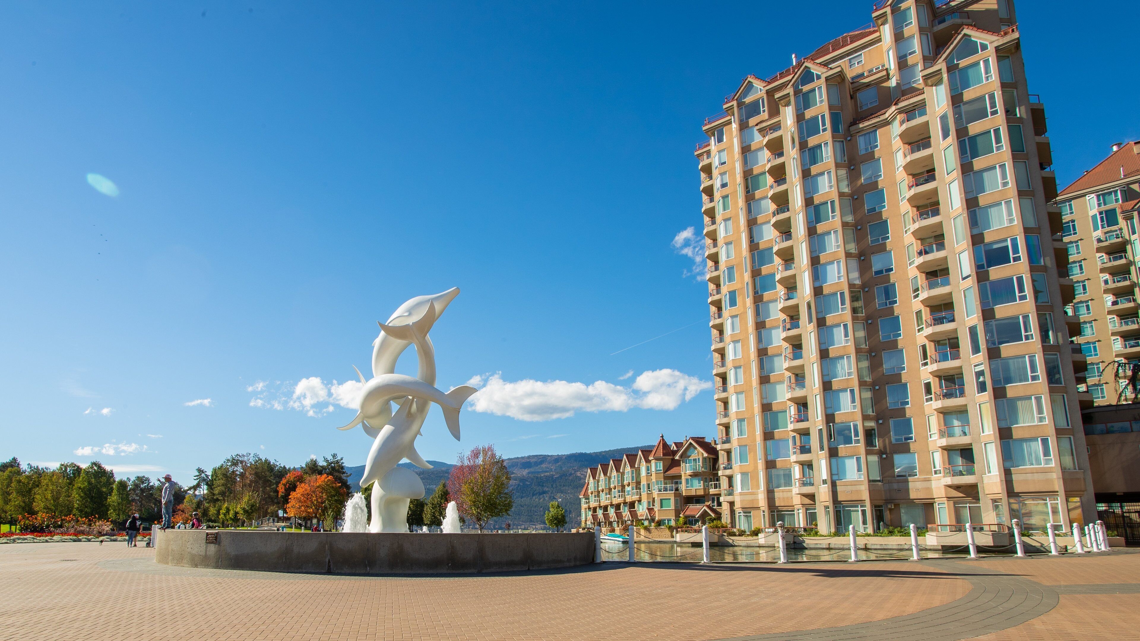 A modern apartment building, a white sculpture, and a clear blue sky.