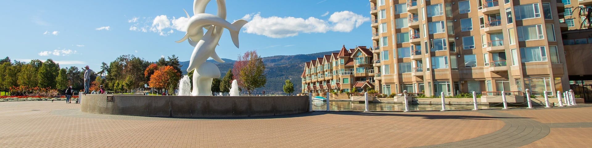 A modern apartment building, a white sculpture, and a clear blue sky.