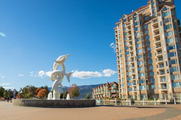 A modern apartment building, a white sculpture, and a clear blue sky.
