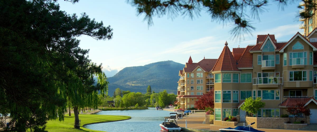 A lake with boats, a river, and a row of buildings with red roofs.
