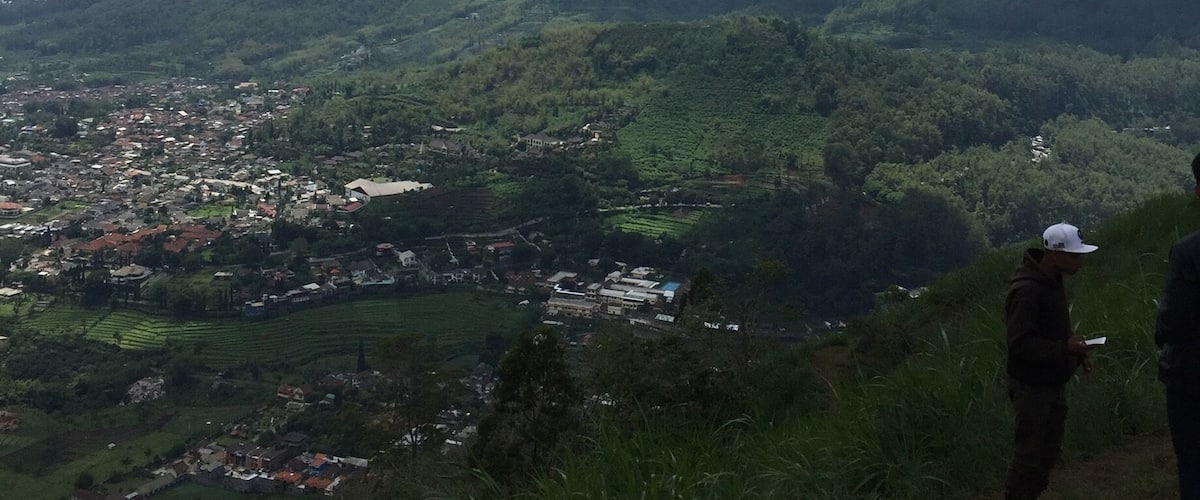 A person paragliding over a mountainous landscape with a village below.