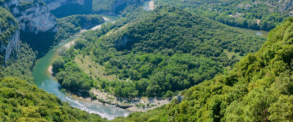 A river winding through a lush valley with steep cliffs and dense forest.