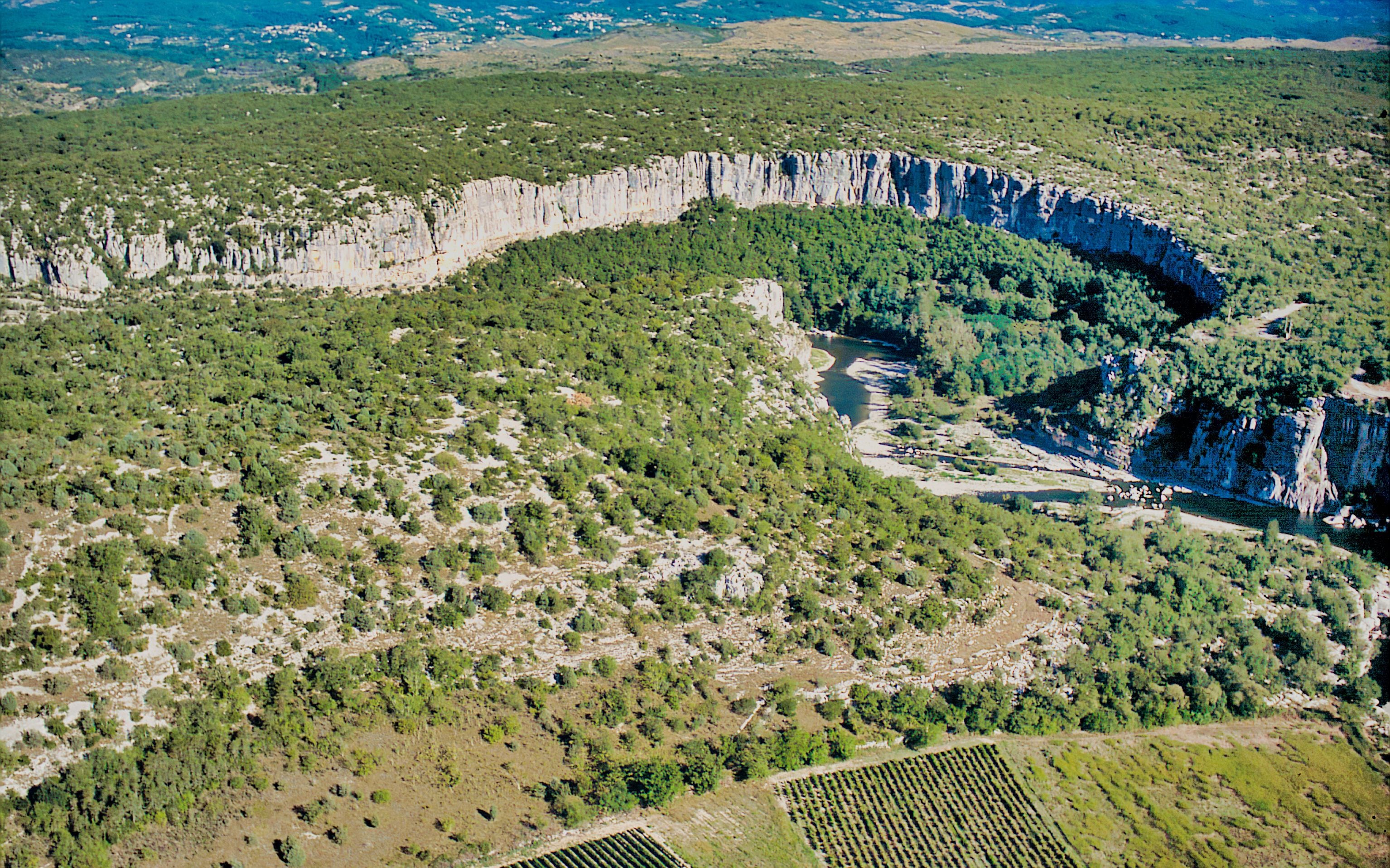 Un fiume serpeggia attraverso una valle, con ripidi pendii e vegetazione fitta.