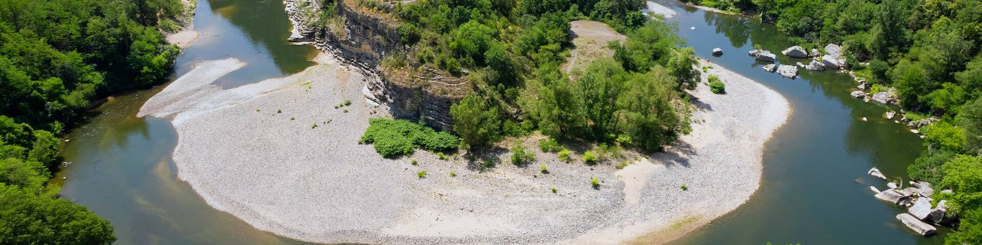 A river meandering through a forested area with a sandy island in the center.