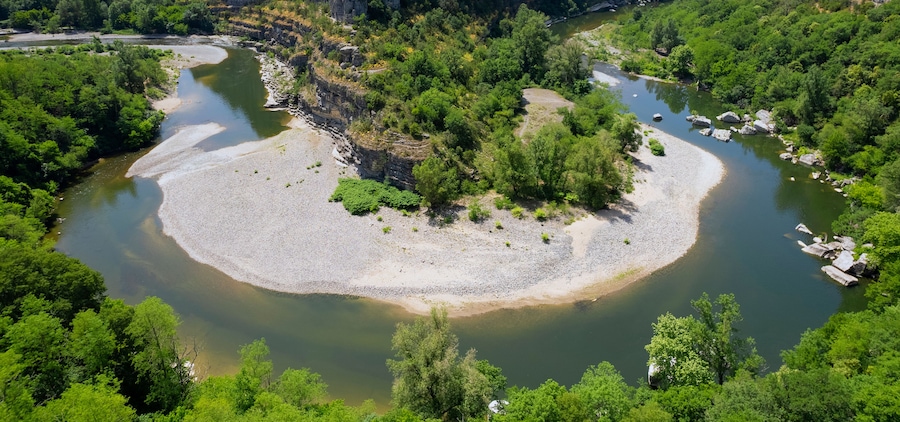 A river meandering through a forested area with a sandy island in the center.