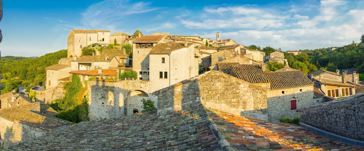 A historic town with stone buildings, terraced roofs, and a hilltop church.