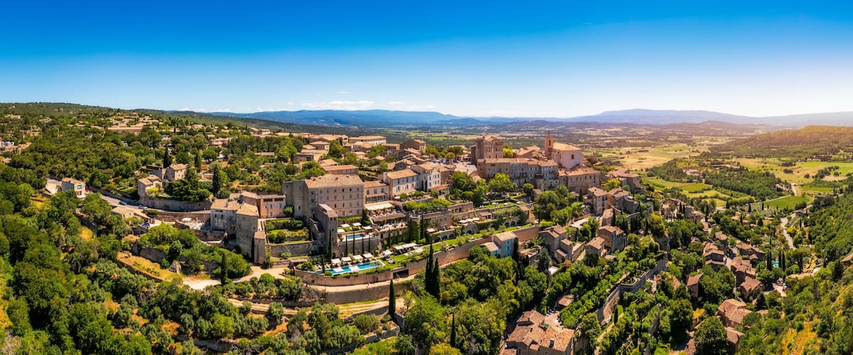 A historic town with medieval architecture, surrounded by lush greenery and rolling hills.