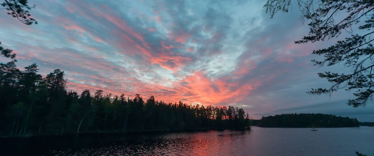 A sunset over a calm lake with a forested shoreline.