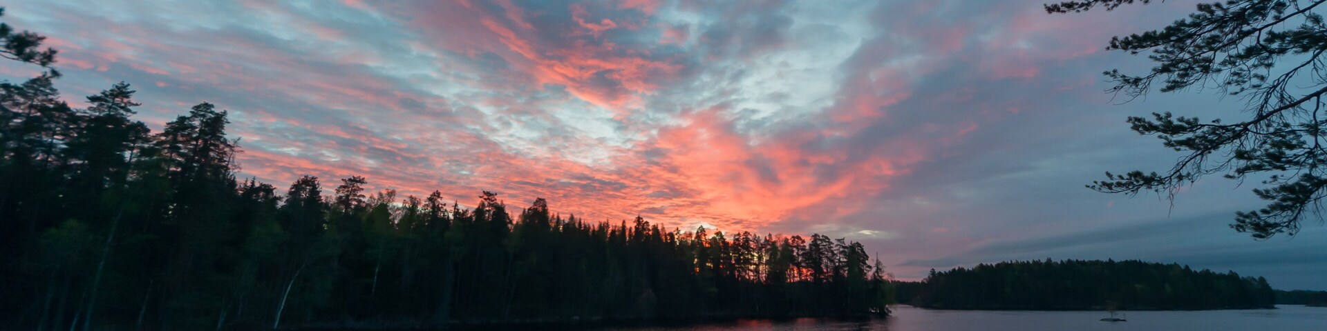 A sunset over a calm lake with a forested shoreline.