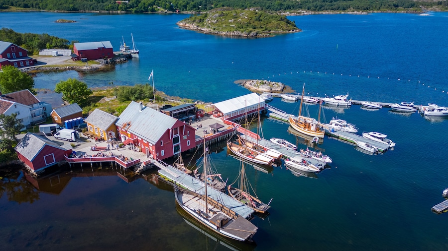 A harbor with boats, a red building, and a small island in the background.