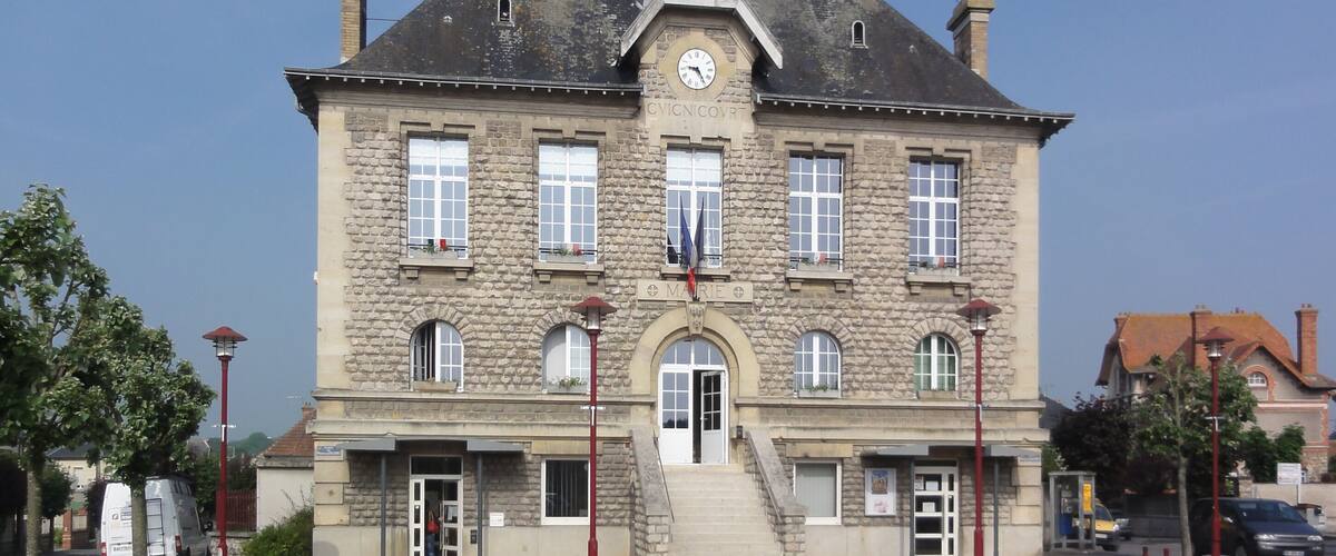 A historic stone building with a clock tower, multiple windows, and a central entrance.