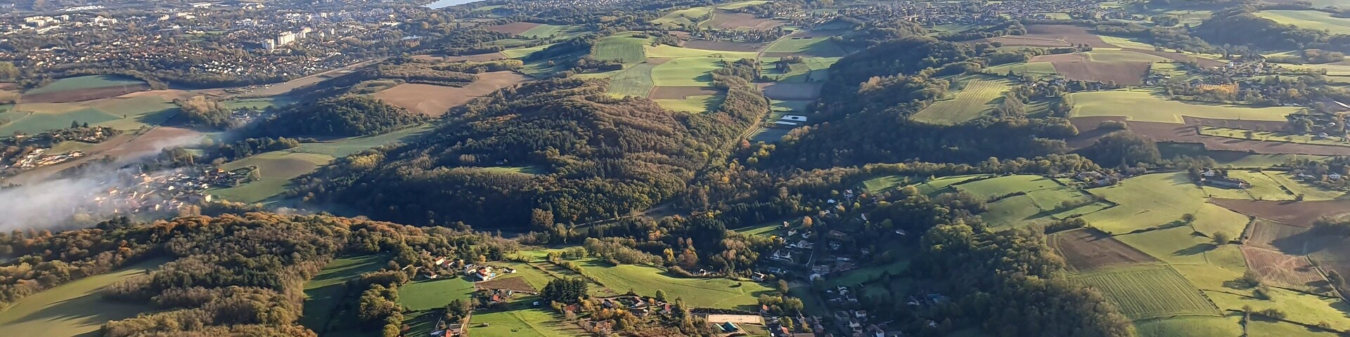 Paisaje rural con colinas onduladas, campos y un pequeño pueblo.