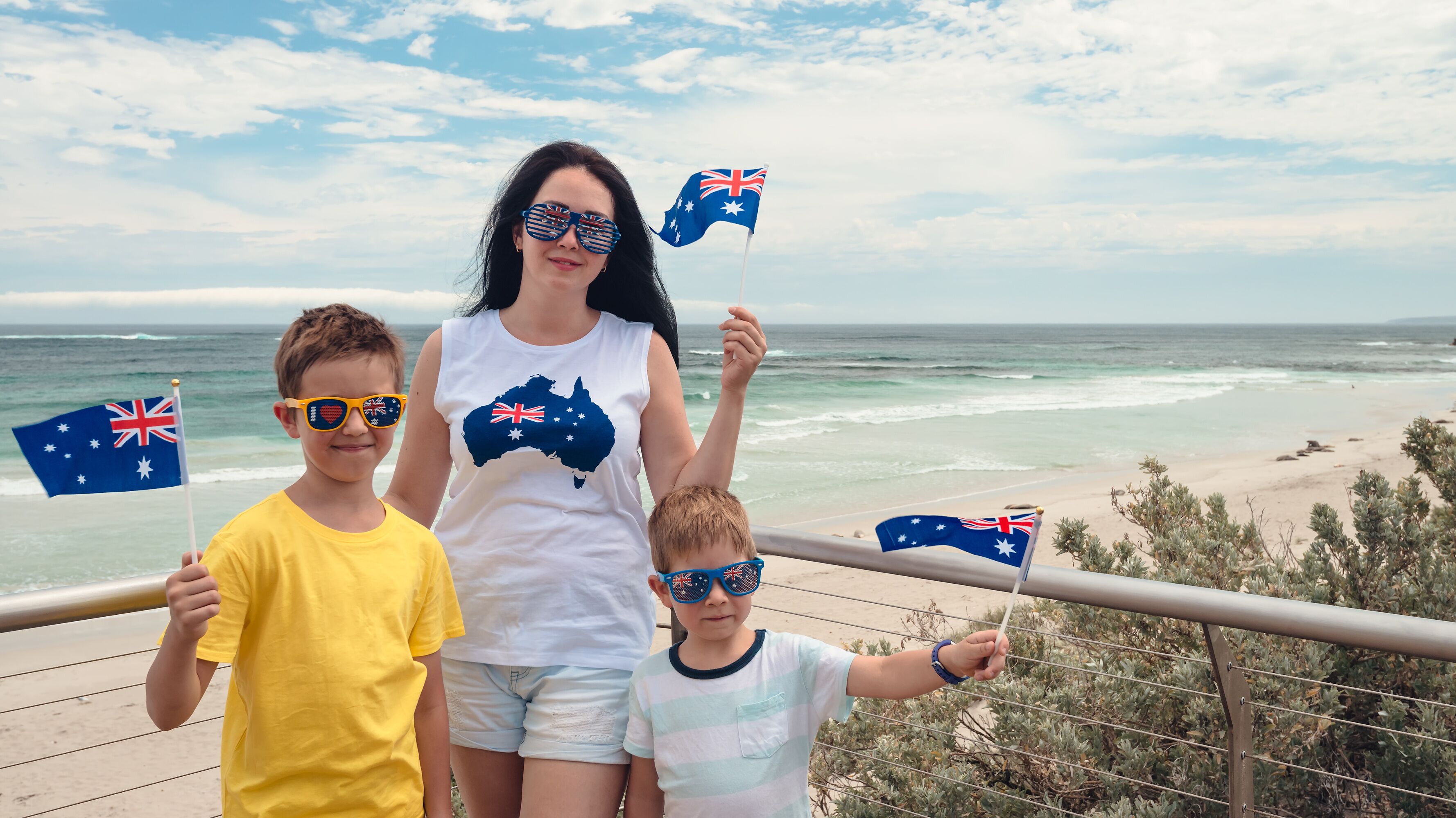 Escena costera con barandilla, olas del océano y banderas australianas.