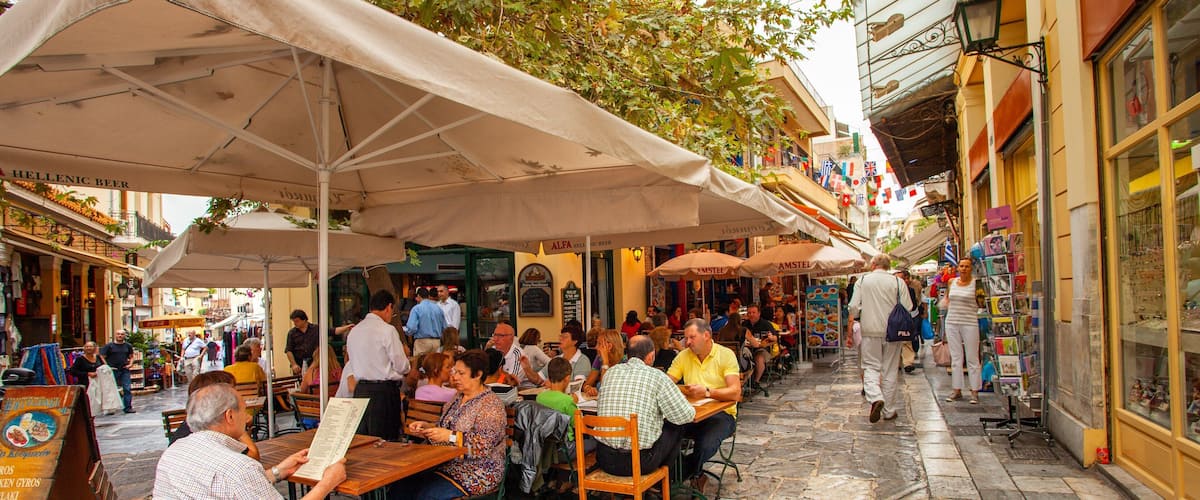 Outdoor seating at a café with umbrellas, a cobblestone street, and various shops.