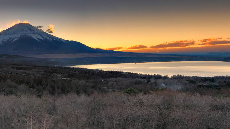 A mountain at sunset with a lake in the foreground.