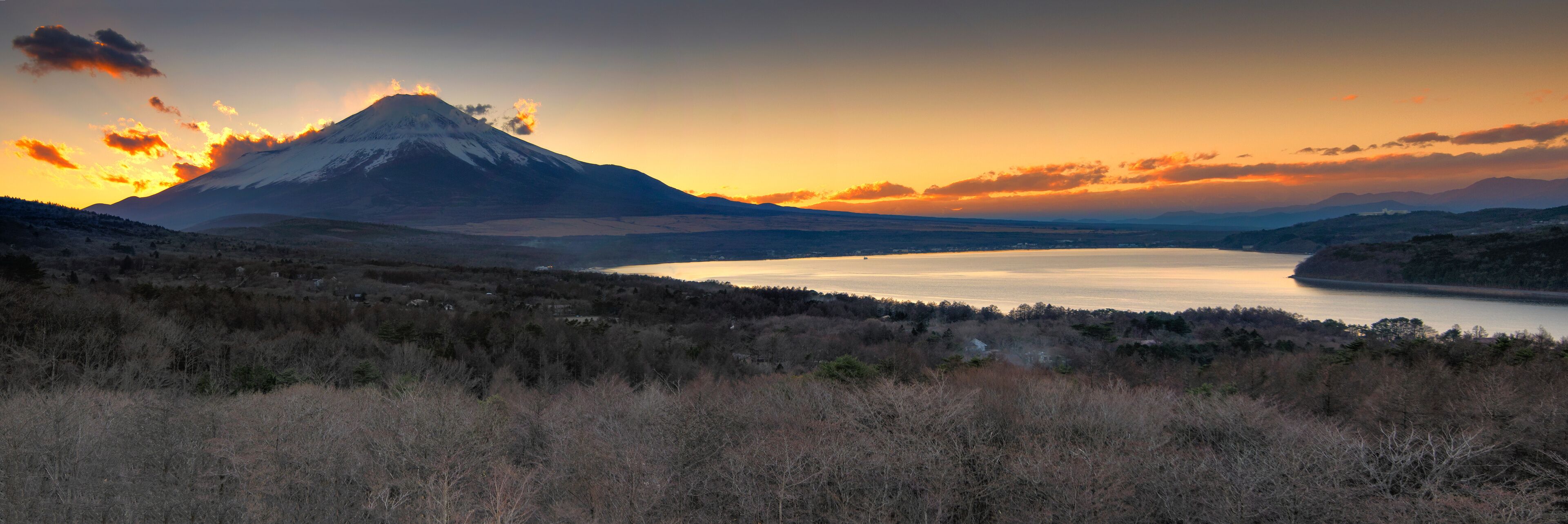 A mountain at sunset with a lake in the foreground.