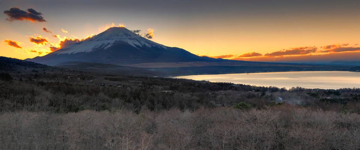 A mountain at sunset with a lake in the foreground.