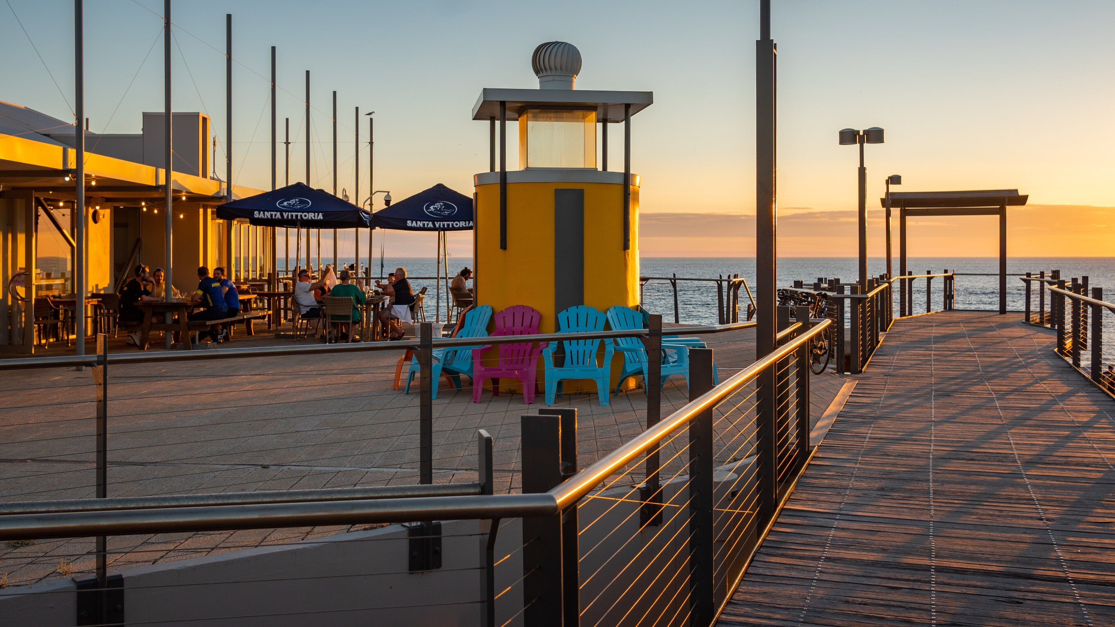 Port Noarlunga showing outdoor eating and a sunset as well as a small group of people