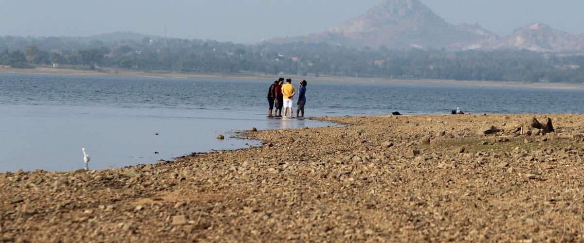 A rocky shoreline with a group of people standing by the water.