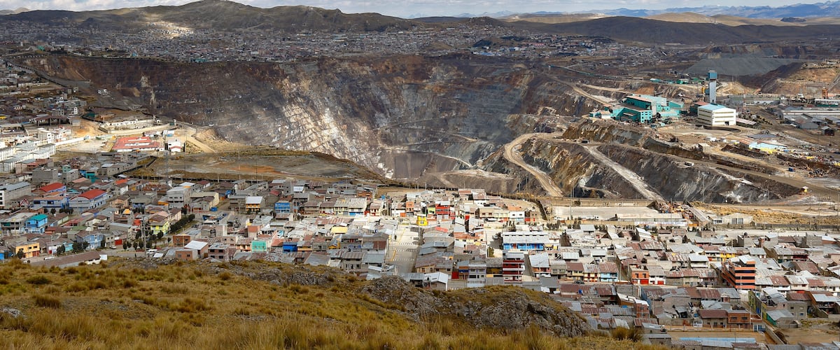 A mining town with a large open pit, buildings, and mountains in the background.