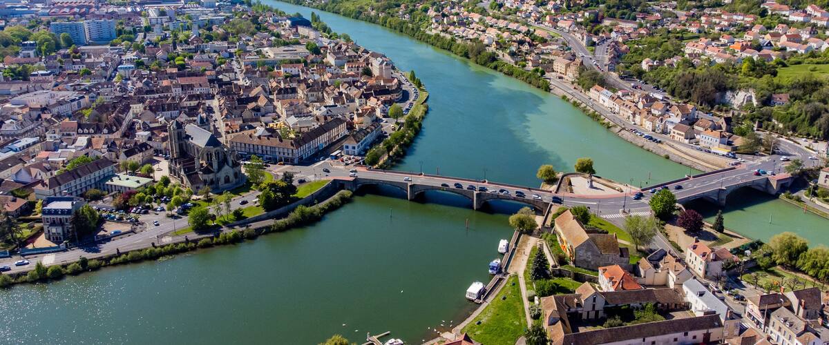 A river winding through a town with historic buildings and a bridge.