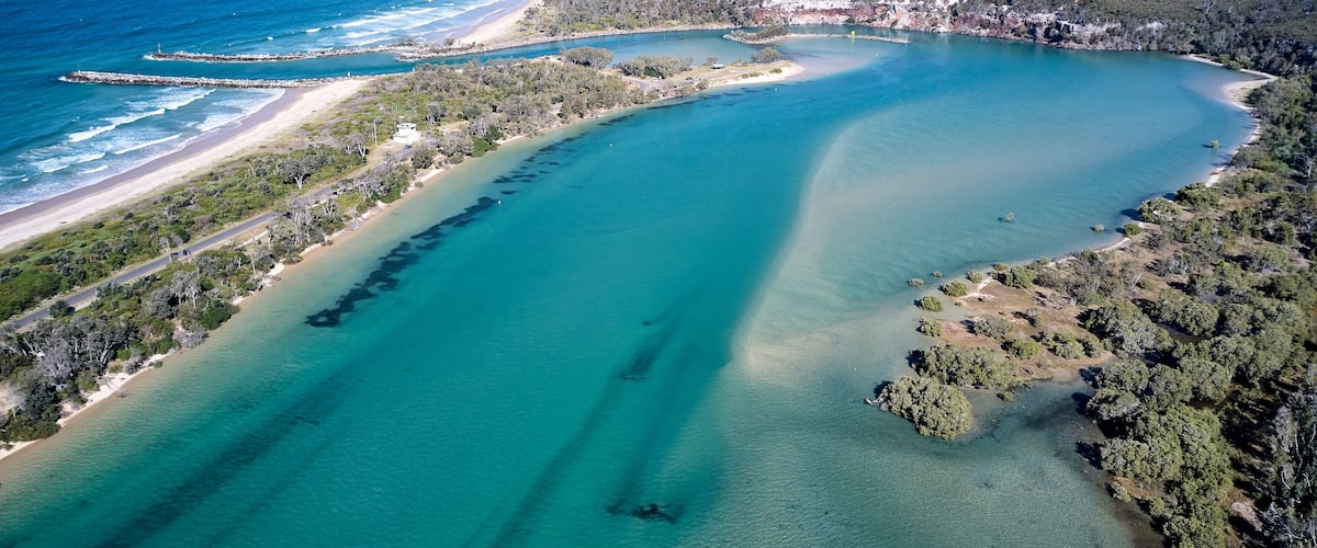 Un paisaje costero con aguas turquesas cristalinas, una playa arenosa y una zona boscosa.