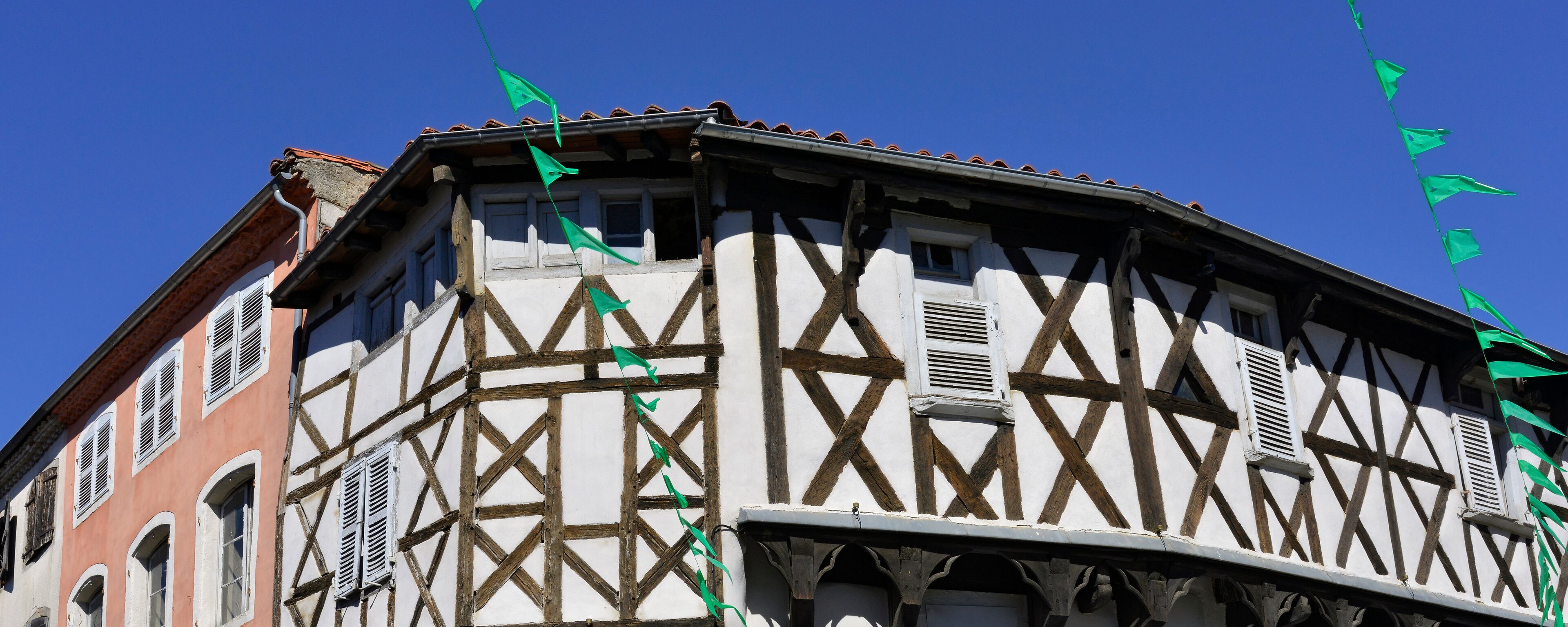 A half-timbered building with green flags.