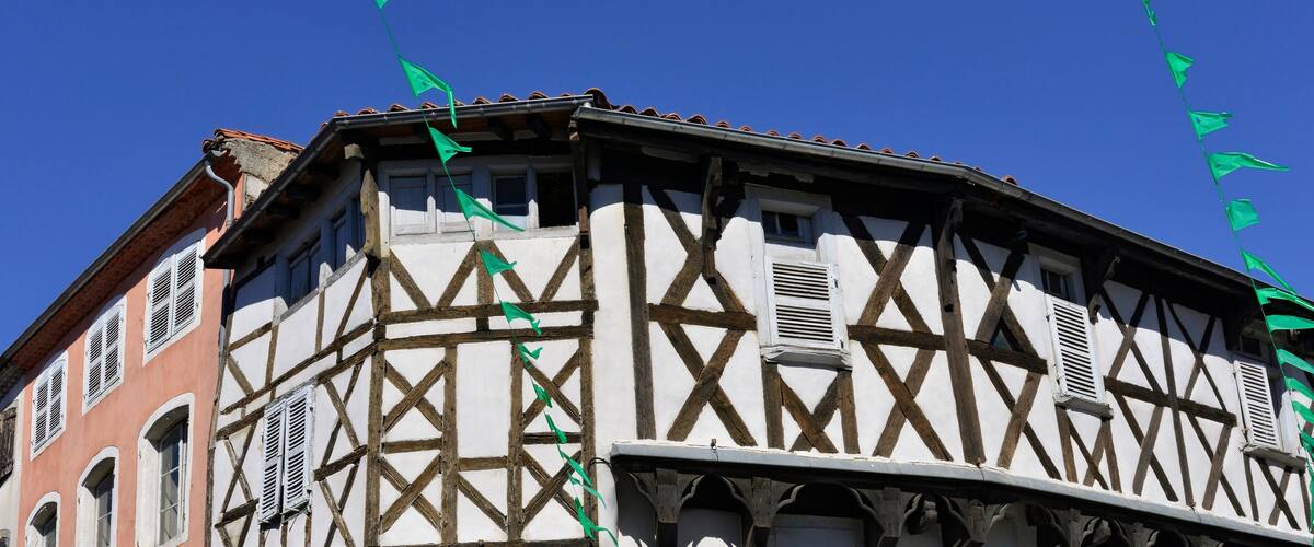 A half-timbered building with green flags.