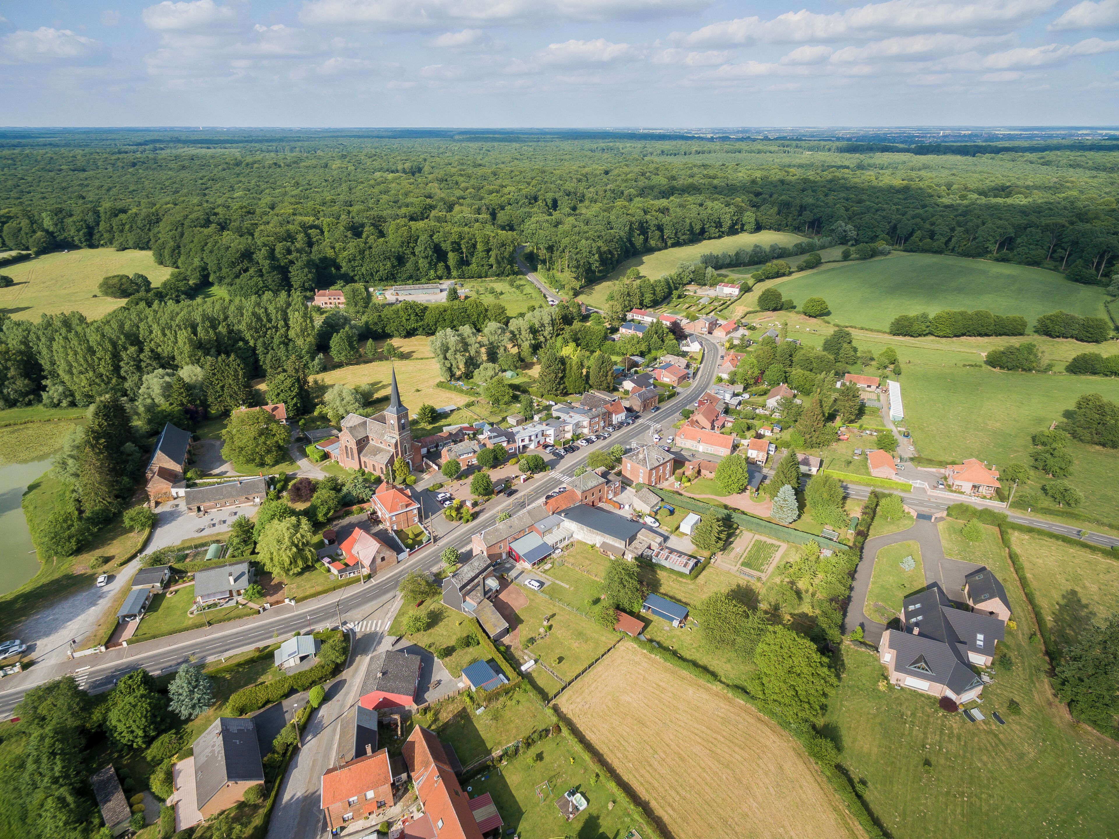 An aerial view of a small town surrounded by lush green forests and fields.