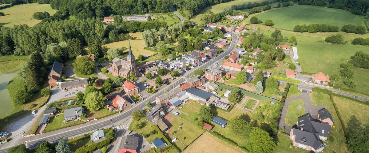 An aerial view of a small town surrounded by lush green forests and fields.