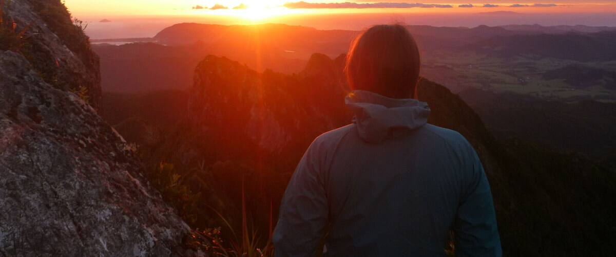A person overlooking a sunset with mountains in the background.