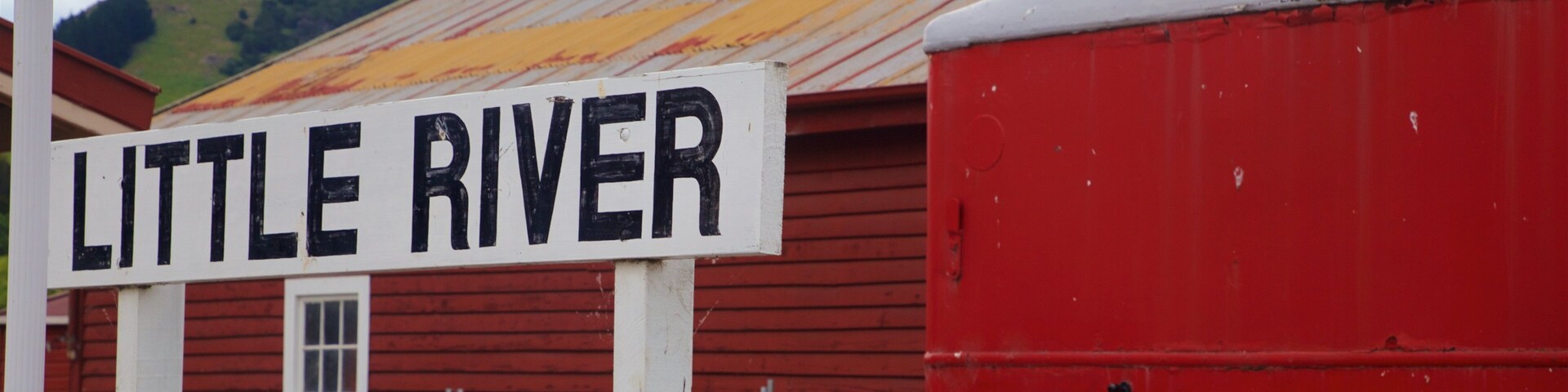 Um edifício vermelho com uma placa que diz 'Little River'.