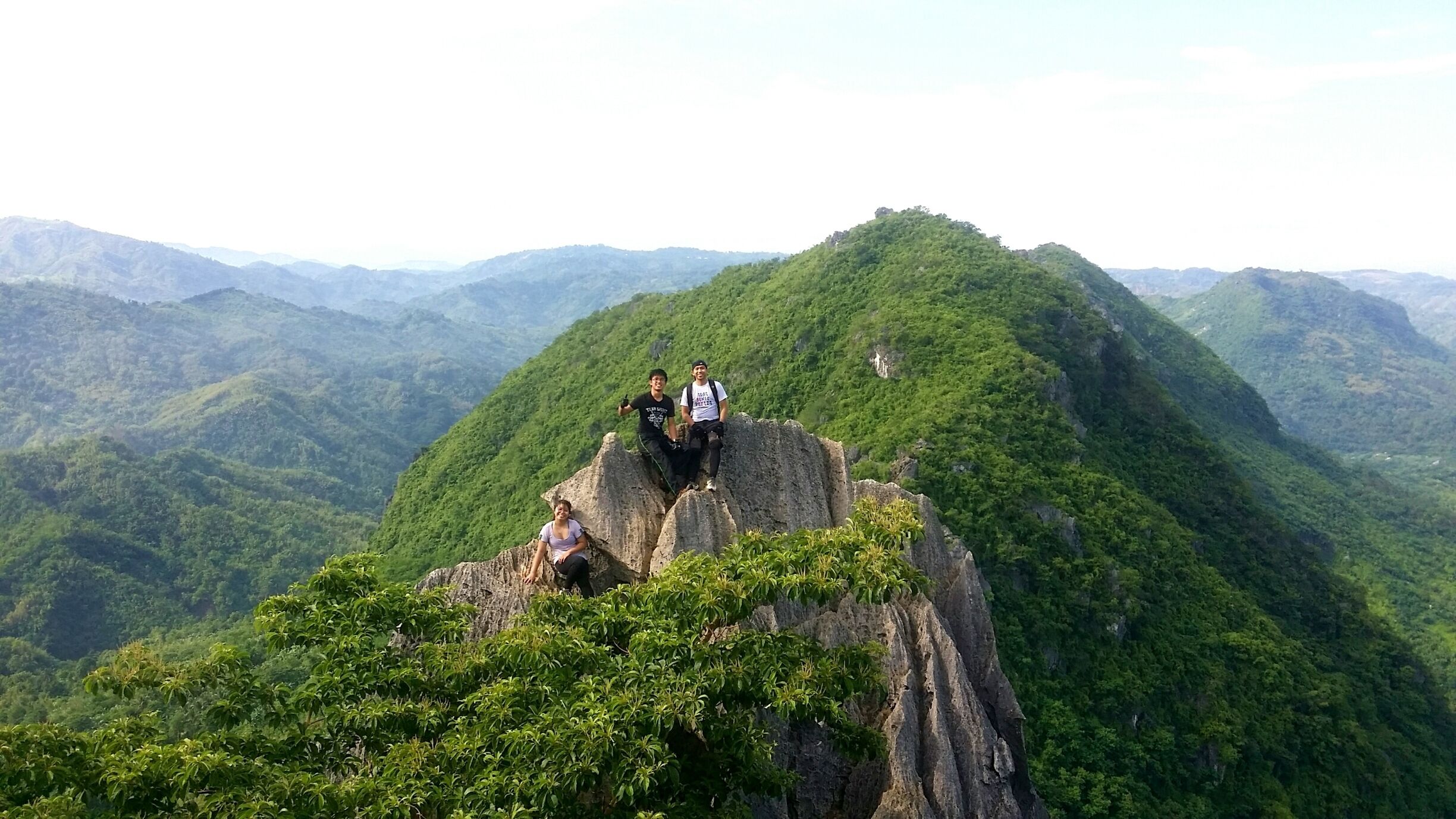 A group of people on a rocky outcrop with lush green mountains in the background.