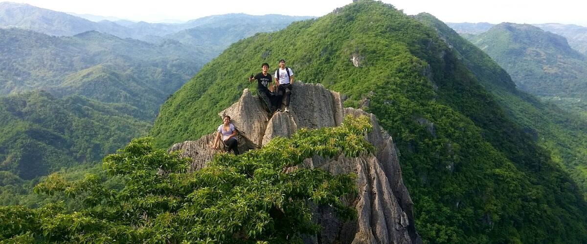 A group of people on a rocky outcrop with lush green mountains in the background.