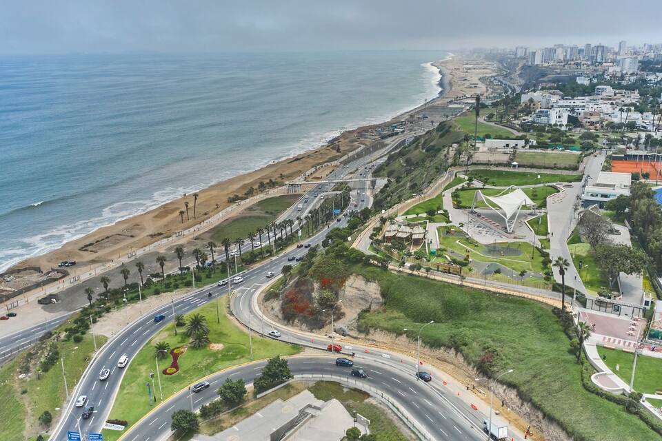 A coastal cityscape with a beach, roads, and urban buildings.