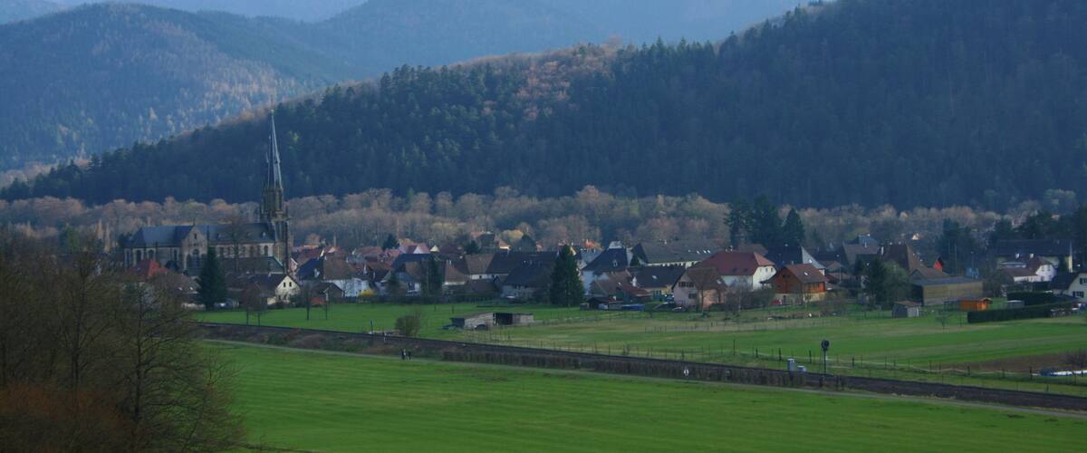 A rural landscape with a church, houses, and rolling hills.