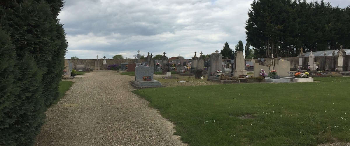 A cemetery with gravestones and a gravel path.
