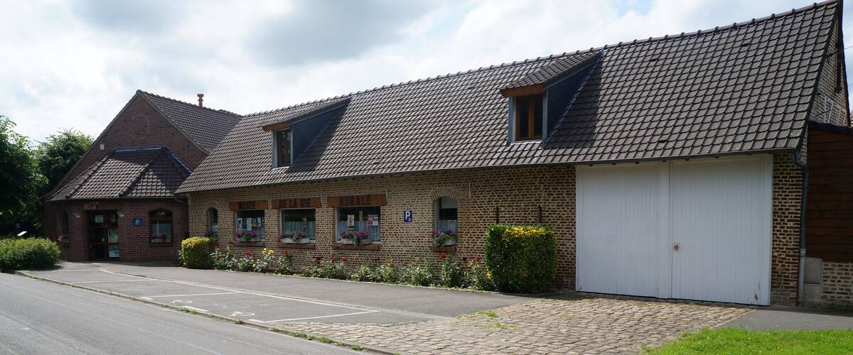 A brick building with a tiled roof, a white garage door, and a parking lot.