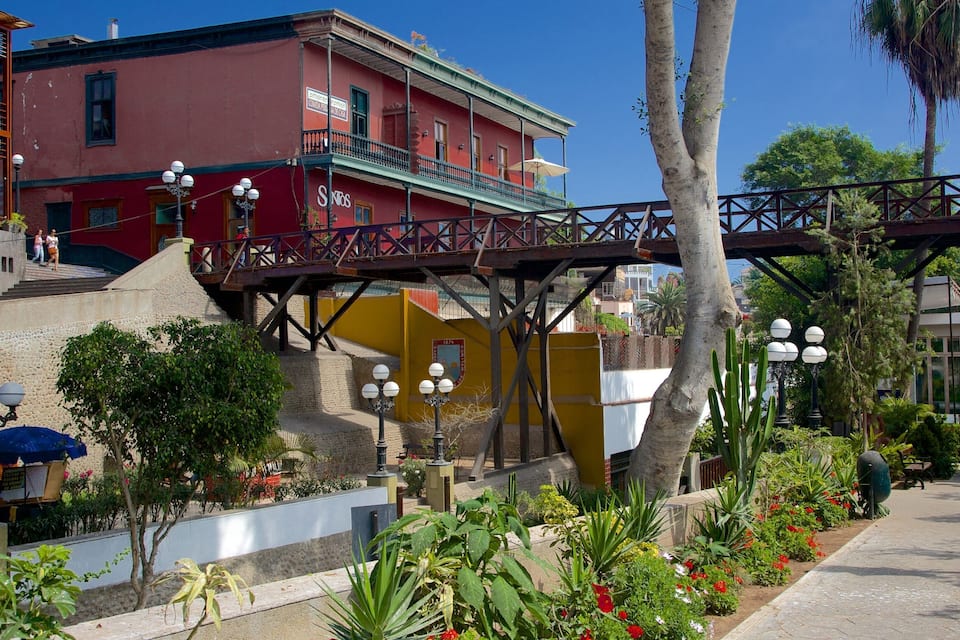 A red building with balconies, a yellow building, and a pedestrian bridge.