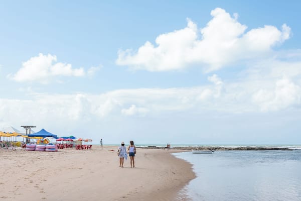 Ein Sandstrand mit Sonnenschirmen, einem Rettungsturm und ruhiger See.