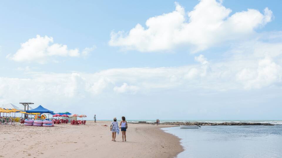 A sandy beach with umbrellas, a lifeguard tower, and a calm sea.