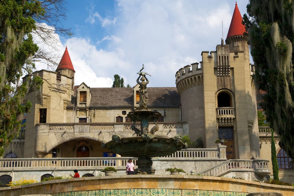 A castle with two red towers, a central fountain, and a tiled walkway.