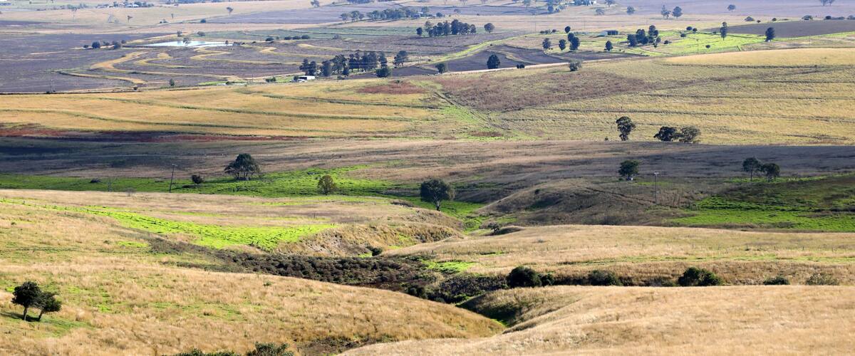 Rolling hills, a river, and scattered trees.