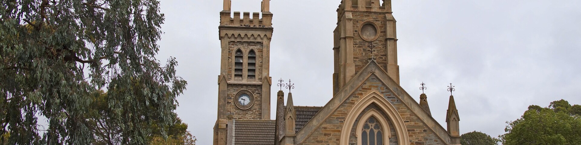 Una iglesia histórica con una aguja alta, una torre del reloj y una amplia entrada en arco.