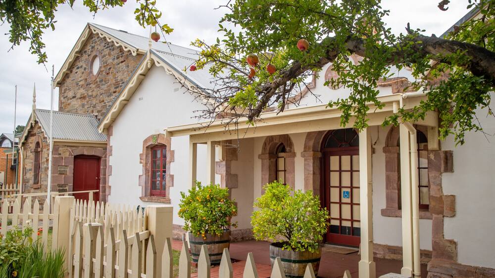 A historic building with a stone facade, a red door, and a white picket fence.