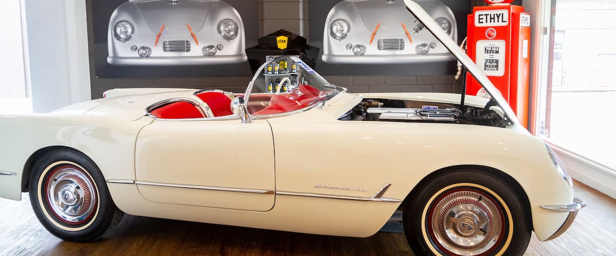 A classic white convertible car with red interior, chrome wheels, and a Chevrolet emblem.