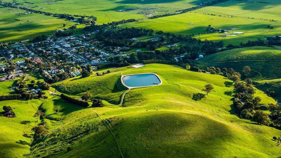 Aerial shot of a rural landscape featuring a lake and green fields. Toora, Victoria, Australia.