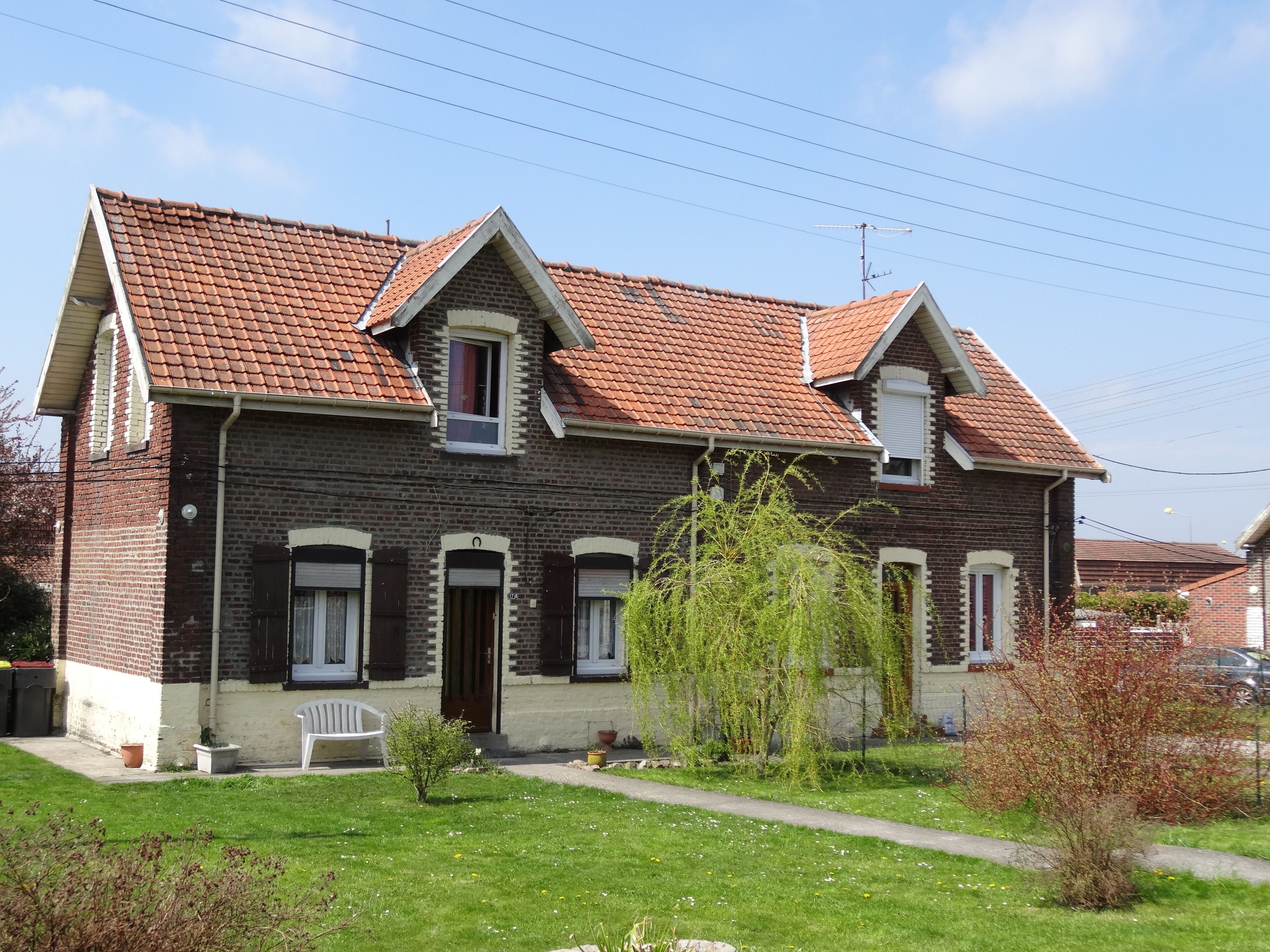 A two-story brick house with a red-tiled roof and a small front porch.